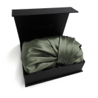 Green satin bonnet in a black box on a white background