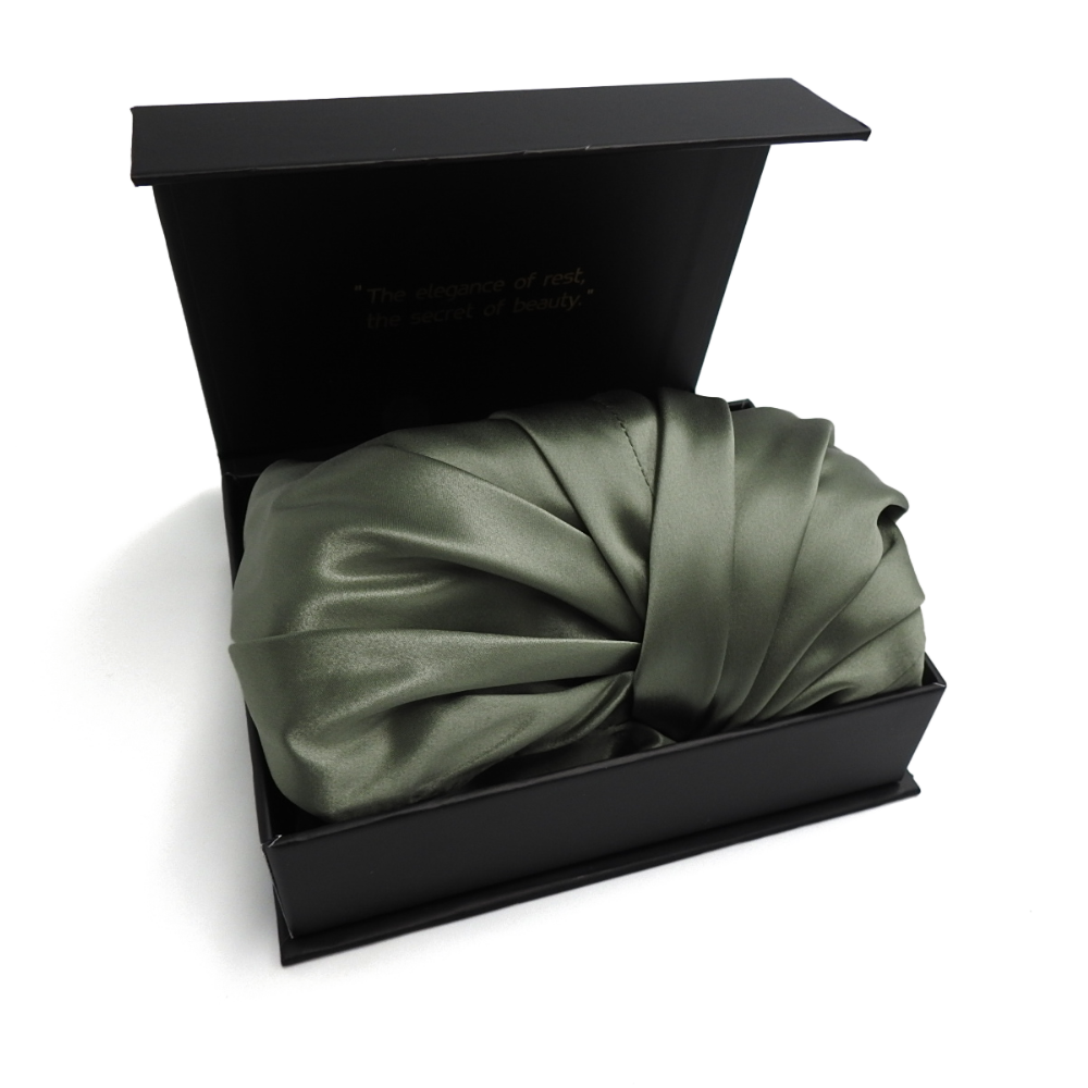 Green satin bonnet in a black box on a white background