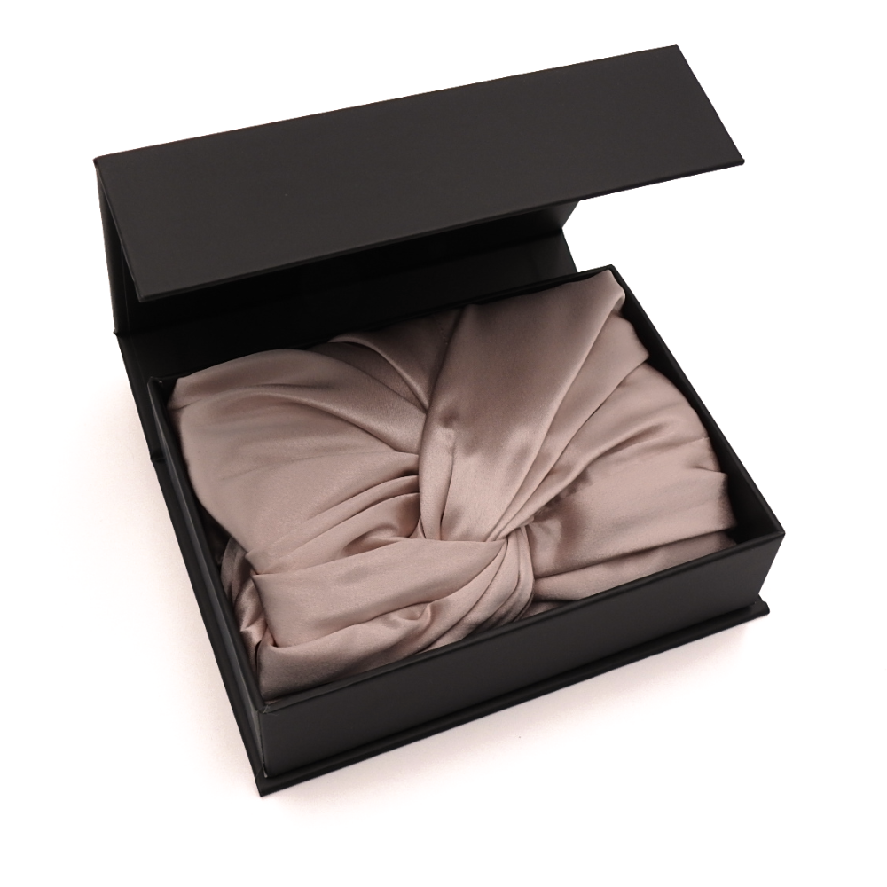 Pink bonnet in an open black box on a white background