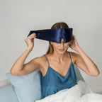 Woman wearing a blue silk eye mask in bed