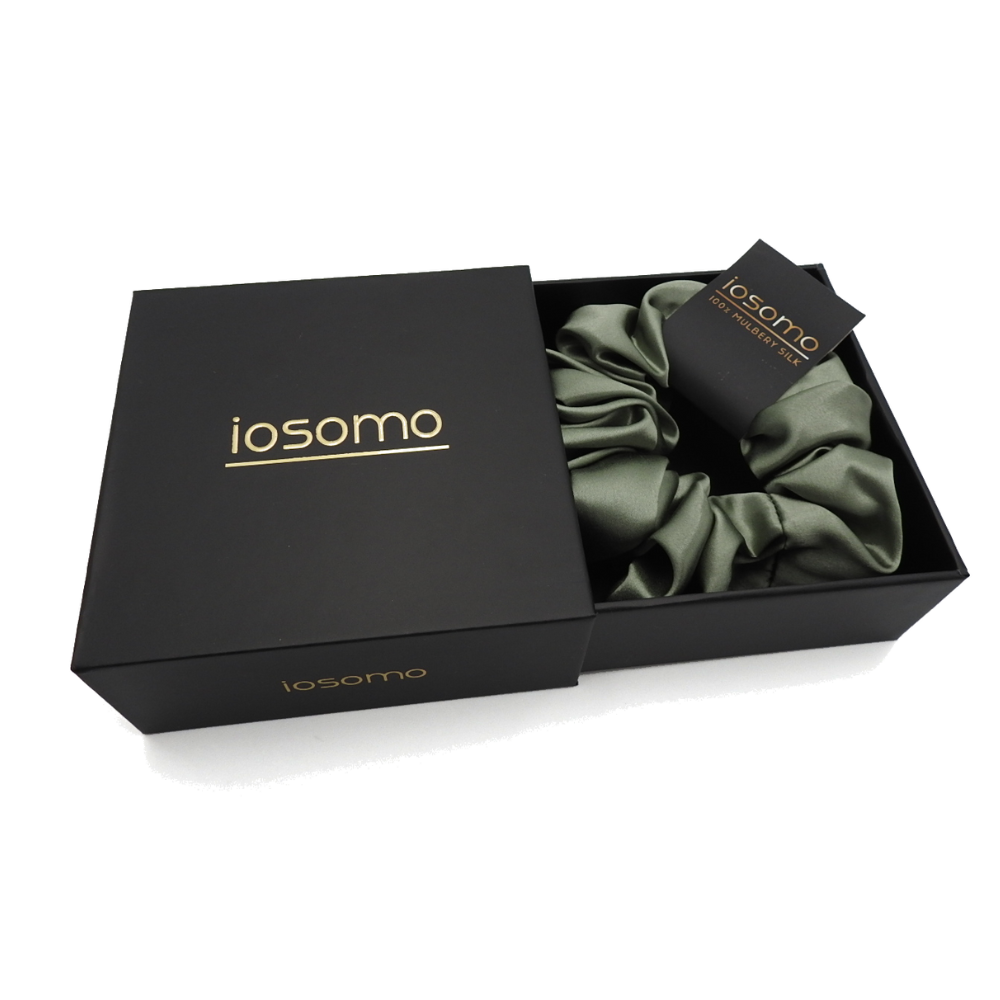 Green satin scrunchie in a black 'iosomo' box on a white background