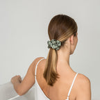Woman with a green scrunchie in her hair against a plain background
