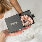 Person holding an open box with pink scrunchies and 'iosomo' branding.